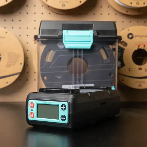 Polymaker PolyDryer Dry Dock Modul für Filamenttrocknung auf einem Tisch mit 3D-Druck-Filamentrollen im Hintergrund.