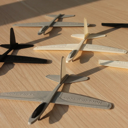 Polymaker PolyLite LW-PLA das leichte PLA Filament, 3D-gedruckte Flugzeuge in verschiedenen Farben auf Holzuntergrund.